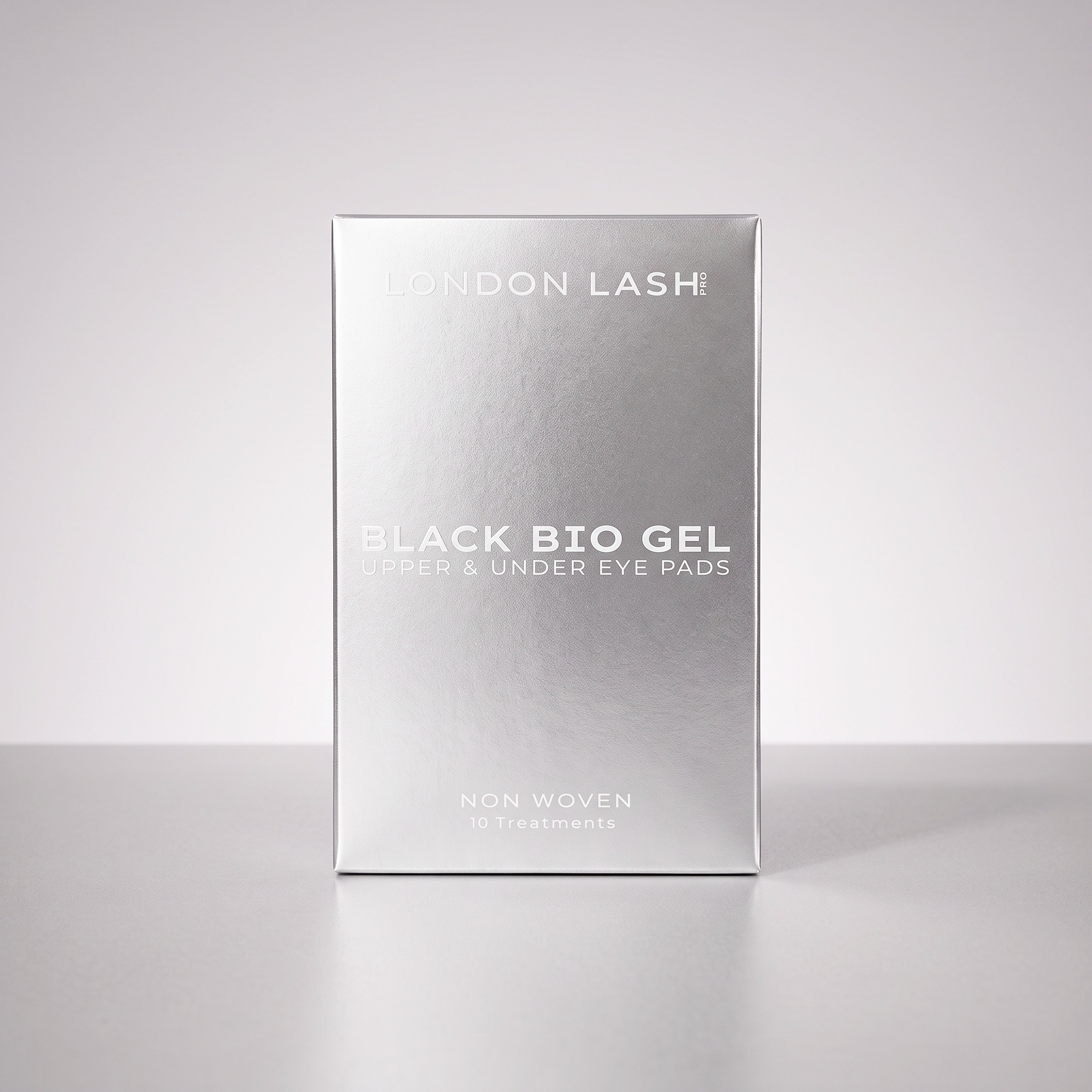 Vue de face de la boîte métallique argentée des patchs noirs bio-gel pour paupières supérieures et contour des yeux London Lash, sur un fond uni en studio.